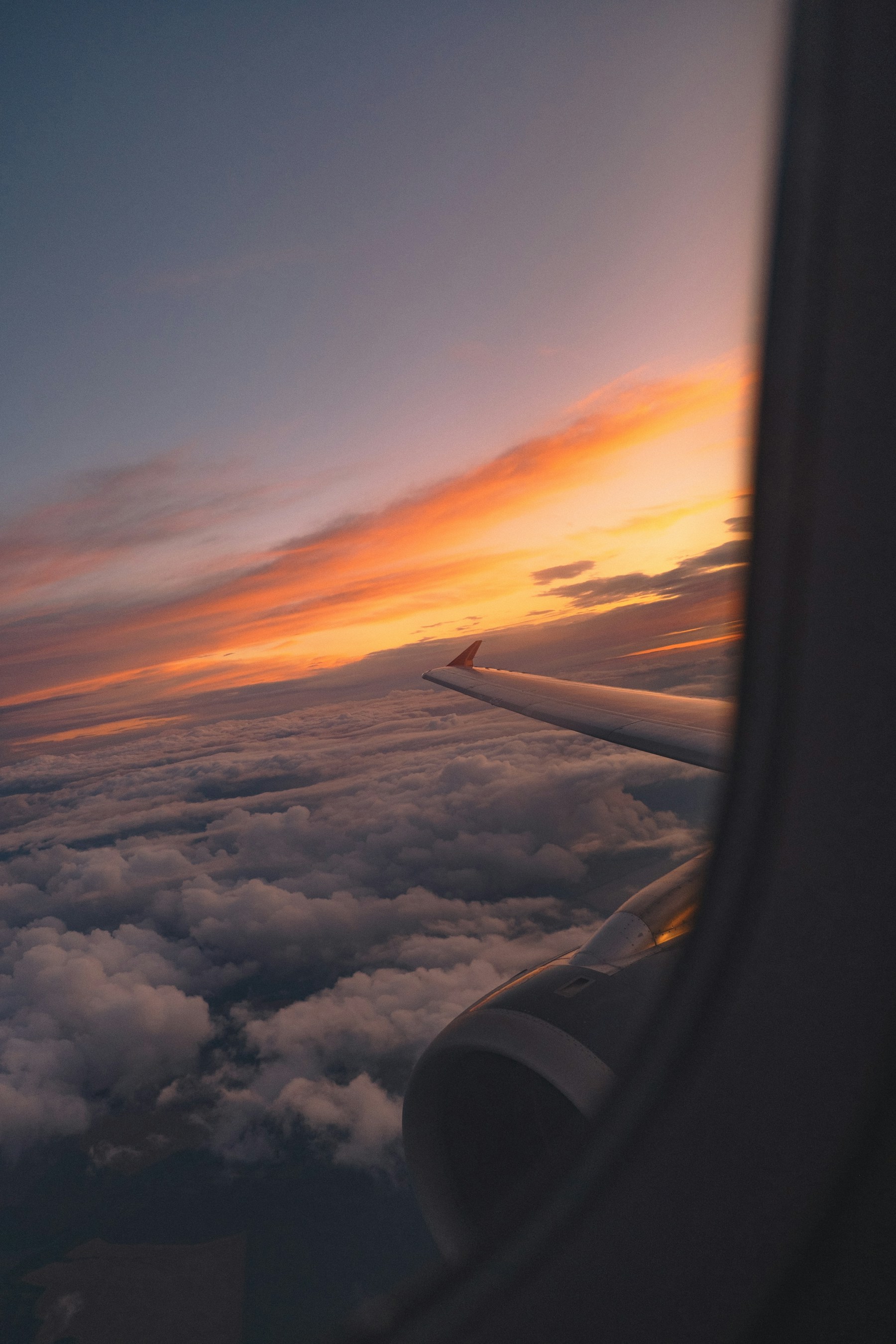 Airplane wing over clouds at sunset